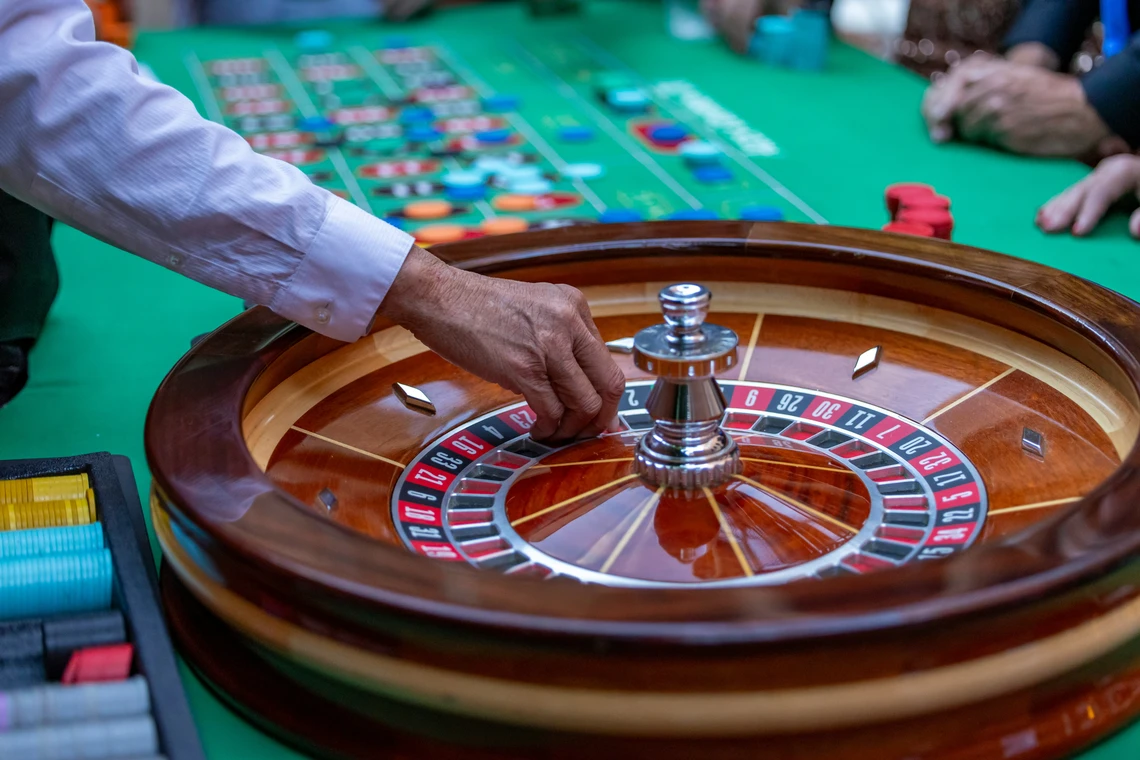 A man is playing a game of roulette on a green table