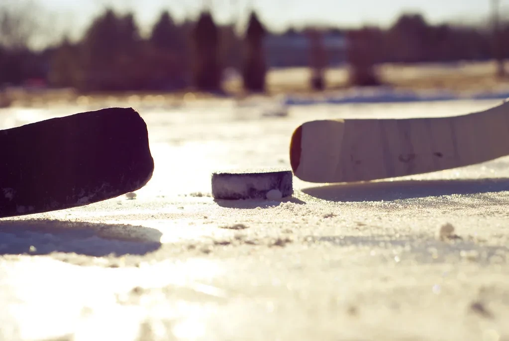 Hockey puck and stick on ice at sunset
