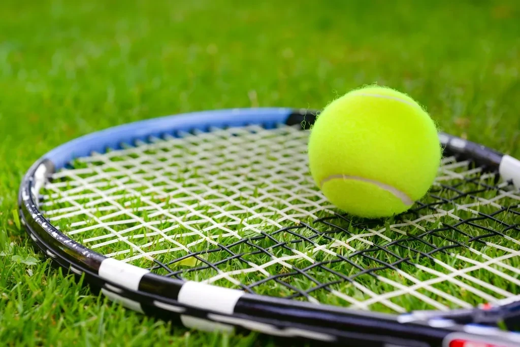 Tennis racket and ball on grass