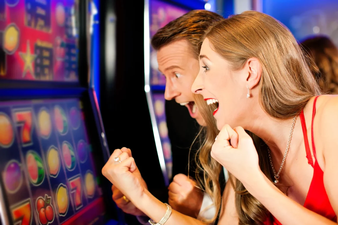Couple cheering in front of a slot machine